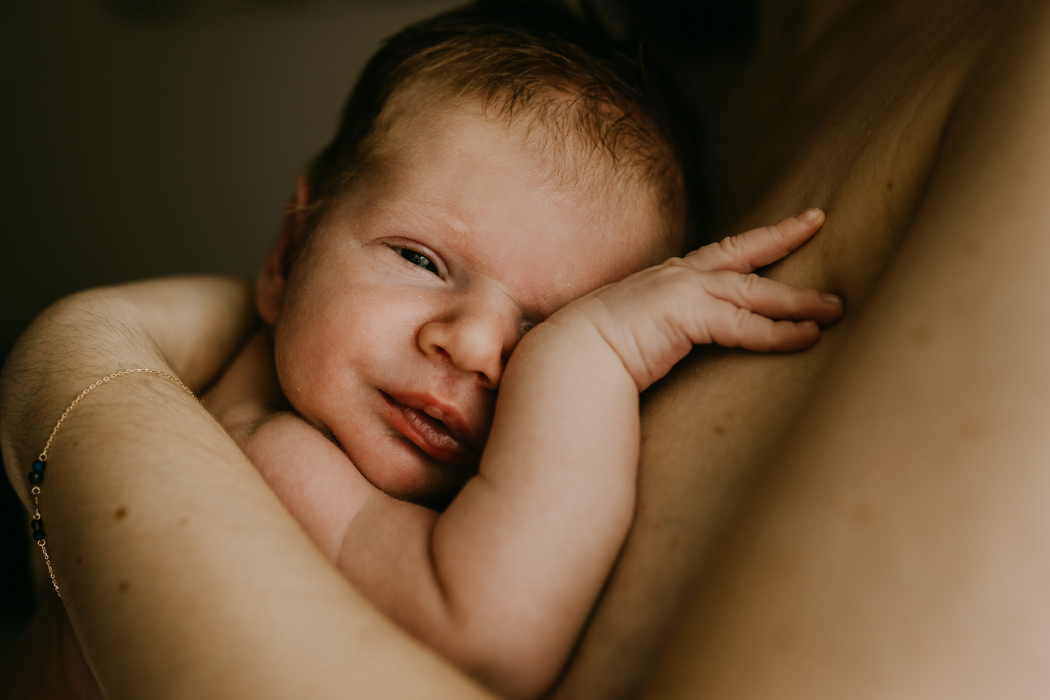 fotografia noworodkowa skóra do skóry na której nagi noworodek przytula się do piersi mamy